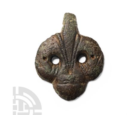5th-7th century A.D.. Flat plaque formed as a facing mask with triangular beard extending from beneath the nose, two lateral 