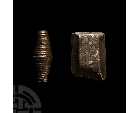 8th-11th century A.D.. Comprising: a fusiform bead with ribbed outer surface; roughly cut segment of a silver ingot often cal