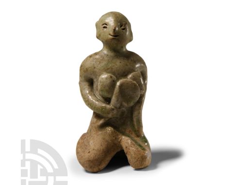 14th-16th century A.D.. Modelled in the round with celadon glaze, a nursing mother kneeling and naked with suckling child hel