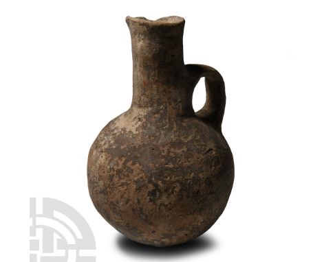 Middle Bronze Age, circa 2000-1650 B.C.. Globular in profile with tall tubular neck and slightly everted rim, loop handle to 