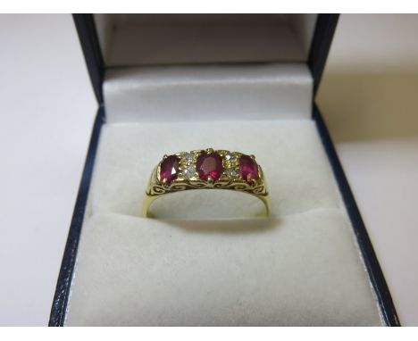 RUBY & DIAMOND RING, 3 stone ruby ring indispursed by small diamonds on a 18ct yellow gold mount, size R/S