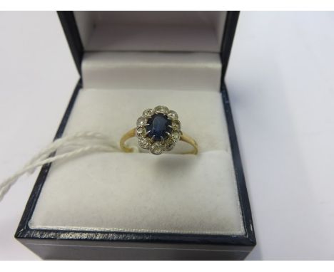 SAPPHIRE & DIAMOND CLUSTER RING, an oval sapphire surrounded by cluster of diamonds on 18ct yellow gold band ring, size K/L