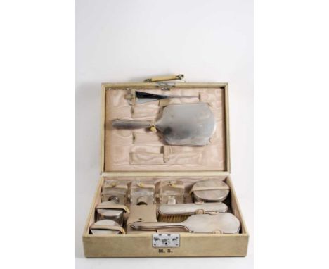 A SMALL MODERN TOILET CASE fitted with a hand mirror, two brushes & various mounted glass boxes/bottles with engine-turned mo