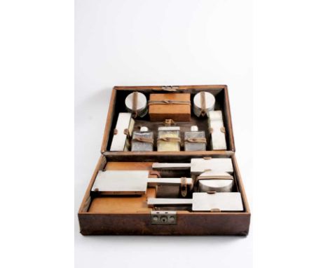 A MODERN TOILET SET in a fitted leather case, including a hand mirror, four brushes, three mounted cut glass cologne bottles,