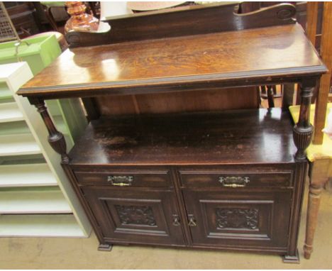 An early 20th century oak buffet with a raised back, shelf raised on turned uprights and a pair of drawers and cupboards on s