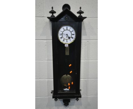A 19TH CENTURY EBONISED VIENNA WALL CLOCK, with a shaped pediment, flanked by two finials, the arched door enclosing a 7 1/4 