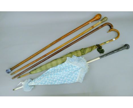 An Eastern silver-mounted parasol, an umbrella and three walking sticks. The former 96 cm long.