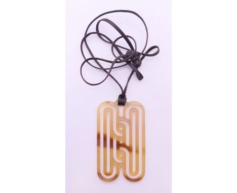A Hermes buffalo horn pendant on leather cord, boxed. The pendant 8 cm high.