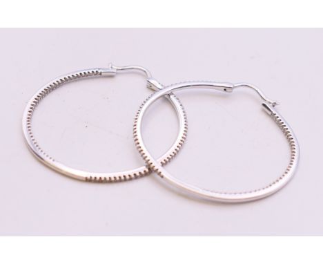 A pair of 14 K white gold diamond hoop earrings. 3.5 cm diameter.