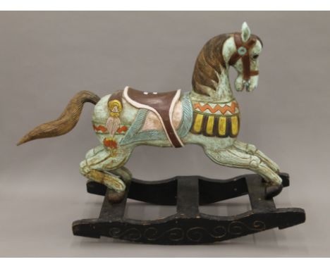 A painted carved wooden rocking horse. 128 cm long.