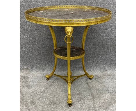 A French gilt metal gueridon or lamp table in the neoclassical style with a marble top above lion's head and paw decoration. 