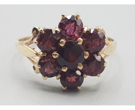 Ladies 9ct yellow gold garnet cluster ring, featuring 7 round garnet stones set in a claw setting, 2.5g gross, size N½