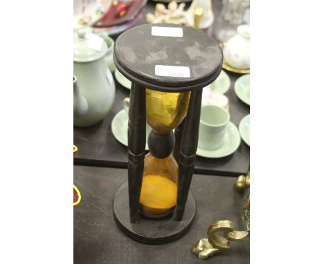 An ebonised wood cased orange glass sand timer