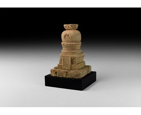 4th-5th century AD. A carved limestone model stupa with tiered base and dome with facing figure of Buddha within an apse, res