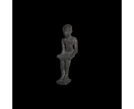 26th Dynasty, 664-525 BC. A silver statuette of the seated scribe Imhotep, holding an open papyrus on his knees above his ple