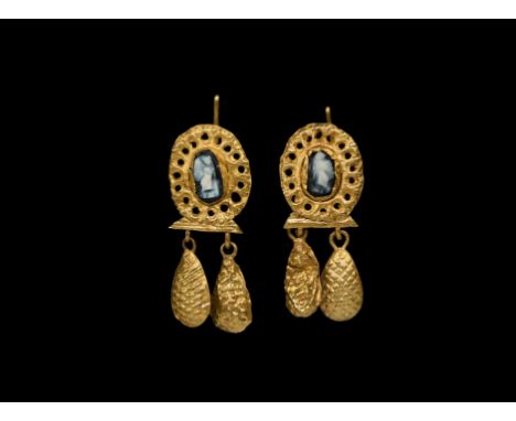 2nd-3rd century AD. A matched pair of gold earrings, each an ellipsoid plaque with openwork floral border and central cell wi