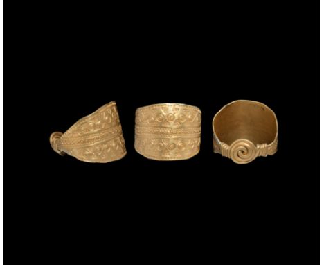 9th-11th century AD. A sheet gold finger ring with bands of stamped pellet, triangle and annulet motifs, the ends coiled into