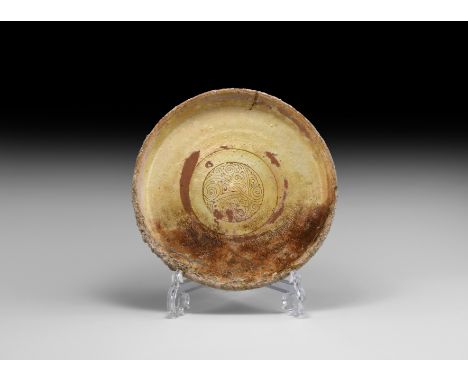 East Mediterranean, 10th-12th century AD. A pale cream ceramic dish with raised rim, painted design of a ring with scrolled t