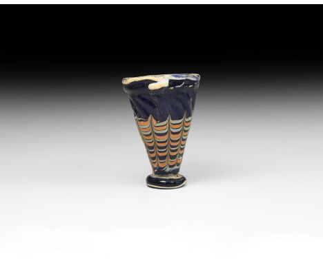 6th-4th century BC. A dark blue glass conical cup with applied trail foot and rim, dragged trails in coral pink and white to 