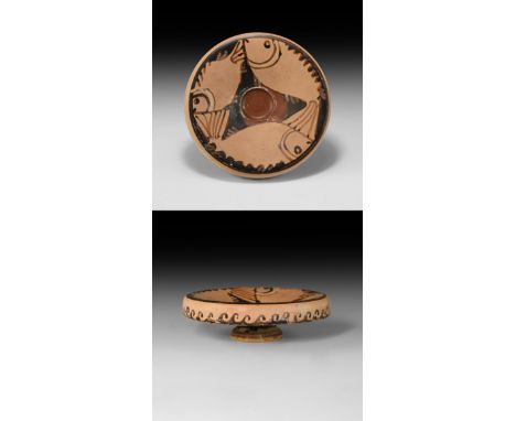 5th century BC. A ceramic dish with pedestal base, flange rim with painted running wave pattern, dished upper face with paint