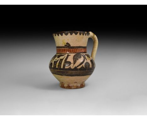 12th-14th century AD. A glazed ceramic jug with biconvex body, flared neck, strap handle with thumb-knop; red band above the 