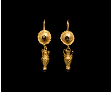 2nd century AD. A matched pair of gold earrings, each a long hook and domed shield with crimped rim and central garnet bead, 