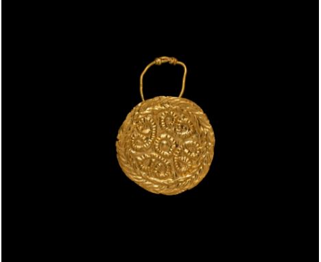 6th-8th century AD. A sheet gold disc with loop to the reverse, suspension hoop with ends coiled round the shank; repoussé de