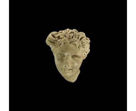 2nd-3rd century AD. A carved marble head of a youthful male with long tousled hair; the eyes deep-set and staring, mouth slig