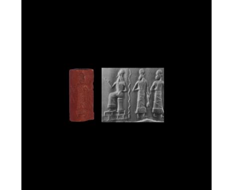 19th-late 16th century BC. A carved red limestone Old Babylonian cylinder seal with worshipping scene; two figures with a hig