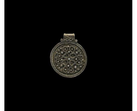 10th-12th century AD. A silver disc pendant with integral loop, granulated border surrounding a panel with filigree ropework 