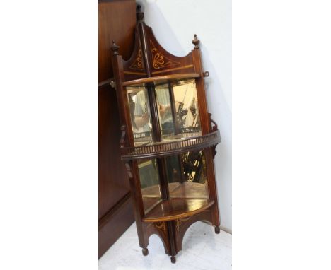 An Edwardian mahogany hanging corner shelf, with three shelves and a mirror back. 106 cm high.