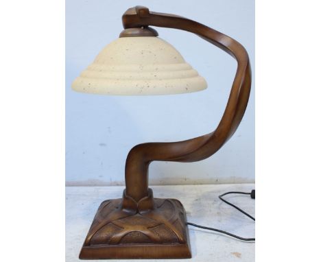 An unusual abstract carved wooden table lamp, with opaque glass shade.