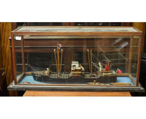 A cased model cargo ship 'Nazim', a diorama with a tug and smaller boat, in a glass display case.