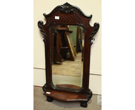 A small mahogany wall mirror, with carved decoration and shelf.