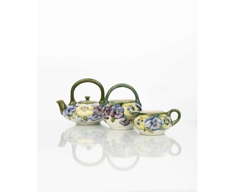 'Pansy' a rare Moorcroft Pottery tea set designed by William Moorcroft, comprising teapot and cover, milk-jug and sugar basin