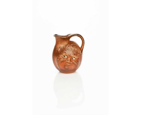 An unusual Martin Brothers stoneware face jug by Robert Wallace Martin, dated 1897, modelled in low relief with a smiling fac