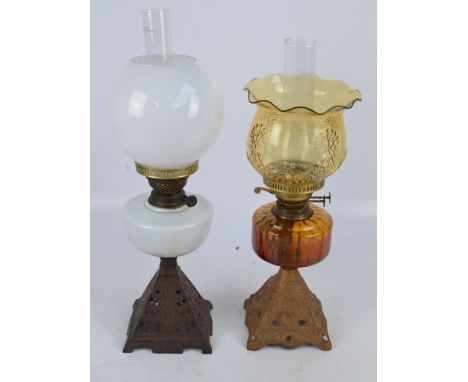 An oil lamp with milk glass body and shade with cast iron pyramid base, an amber glass example and a clear etched glass oil l