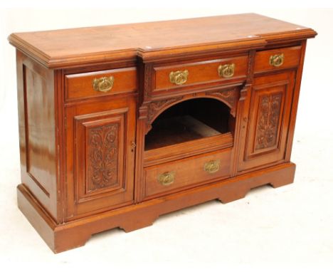 A walnut break front sideboard with three drawers above central compartment flanked by carved cupboard door, on bracket feet,