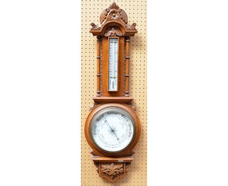 An Edwardian carved oak aneroid barometer with thermometer, length 85cm.