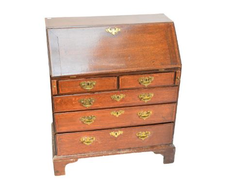 A late George III oak and mahogany crossbanded bureau of small proportions, the fall front enclosing a fitted interior above 