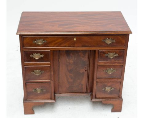 A late 19th/early 20th century mahogany kneehole writing desk with one long drawer, over central cupboard door flanked either