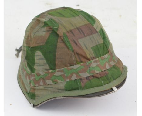 A WWII helmet with leather liner and chin strap and camouflage cover.