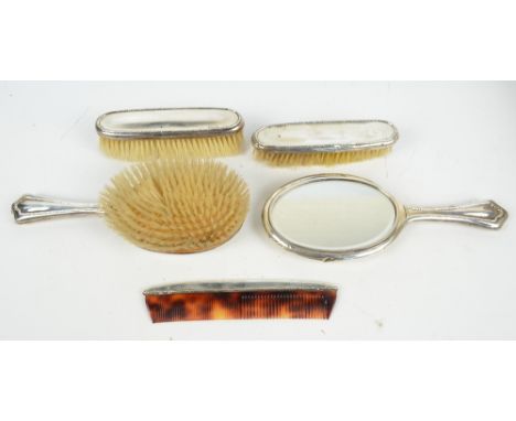 WALKER & HALL; a George V hallmarked silver backed five piece dressing table set comprising an oval hand mirror, length 27cm,