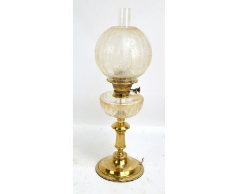A late 19th century brass oil lamp with clear glass reservoir and globular floral decorated shade, height 59cm including funn