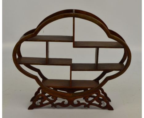 A modern hardwood netsuke display shelves of quadrilobed form, on foliate scroll base, width 39cm (af).