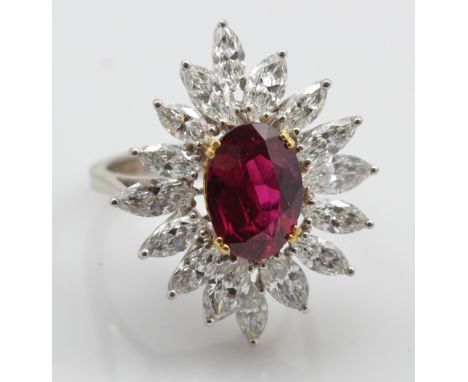 A white metal natural ruby and diamond cluster ring, the oval cut ruby weighing approx 4.50ct set within a border of sixteen 