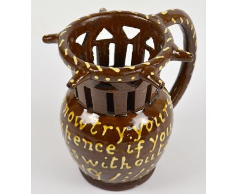 A 19th century treacle glazed slip ware puzzle jug inscribed 'Gentlemen Now Try Your Skill. I'll Lay You Sixpence If You Will
