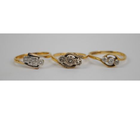 Three 18ct yellow gold three stone rings including an Art Deco style diamond illusion set example, and a white sapphire set e