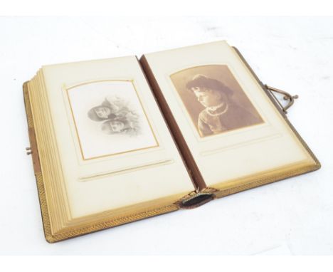 An early 20th century leather bound and brass clasped photograph album containing black and white portrait photographs, parti
