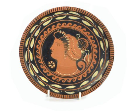 An important Greek plate, Apulia c.330 B.C., centred with the profile portrait of a young woman within a leaf stylised border